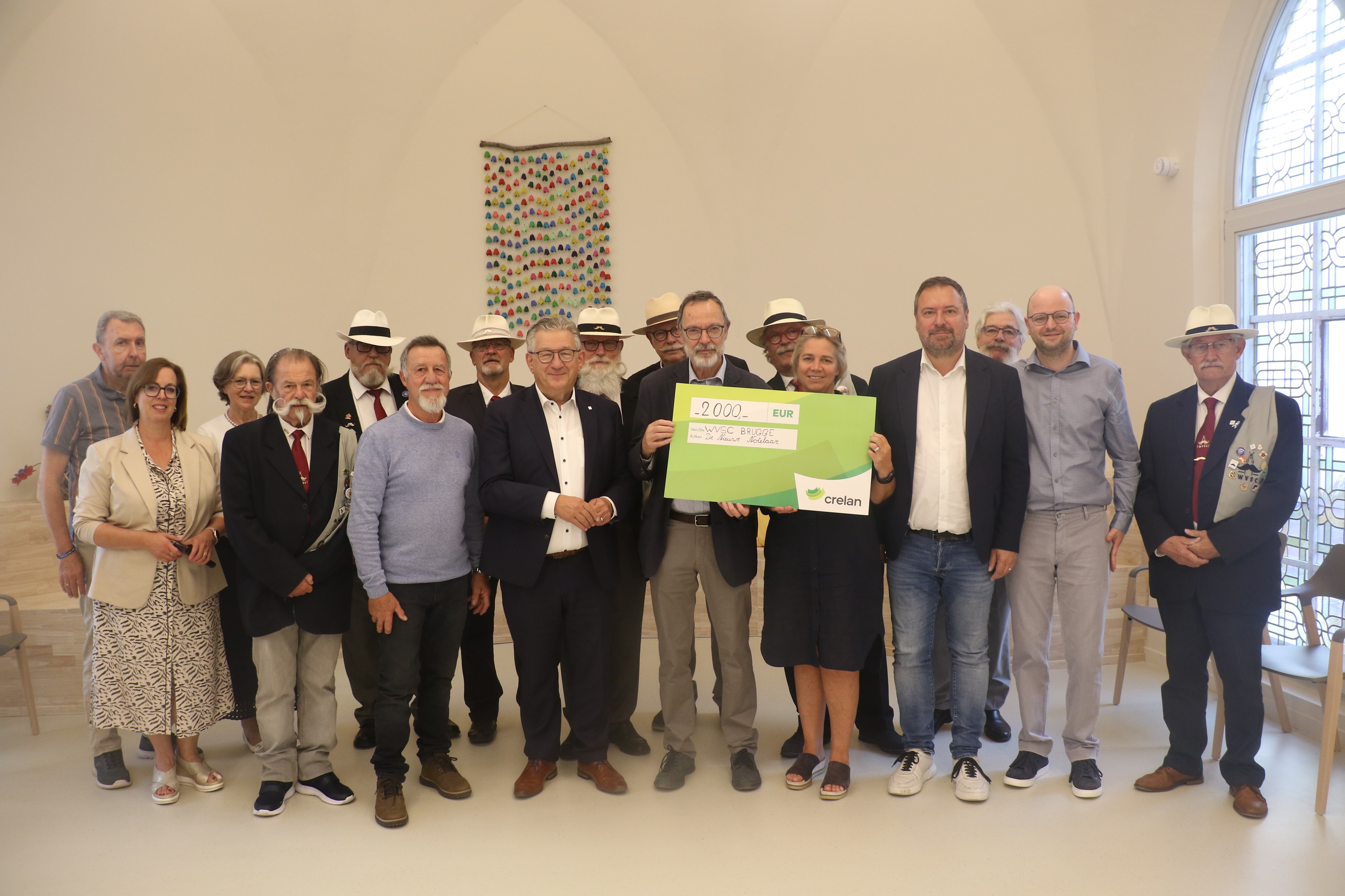 De leden van de West-Vlaamse snorrenclub overhandigen de cheque aan Els Goderis, directeur van de vereniging Ons Huis, die wordt bijgestaan door Brugs burgemeester Dirk De fauw en schepen van sociale zaken Pablo Annys.