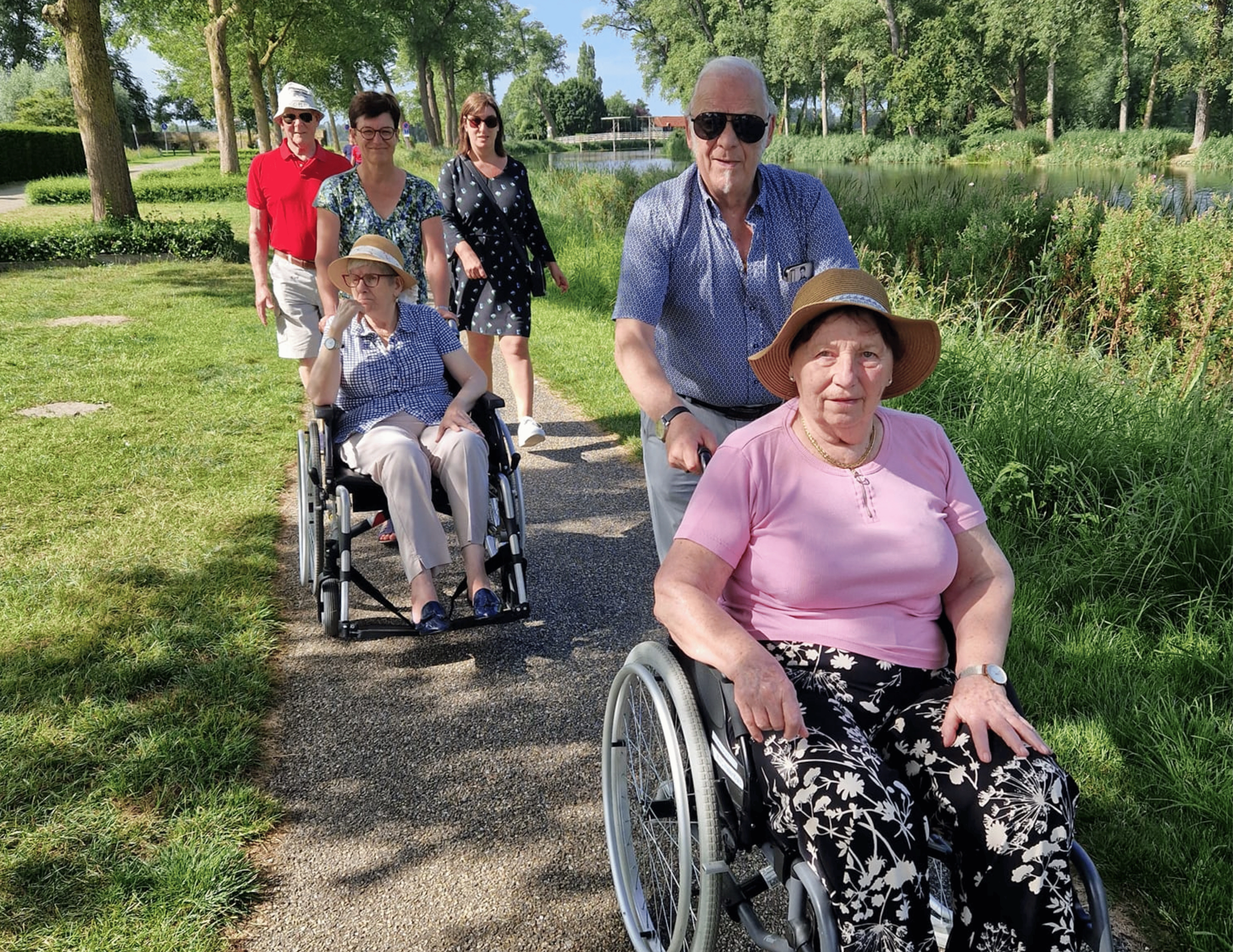 Bewoners in rolstoelen en vrijwilligers maken een wandeling in de natuur