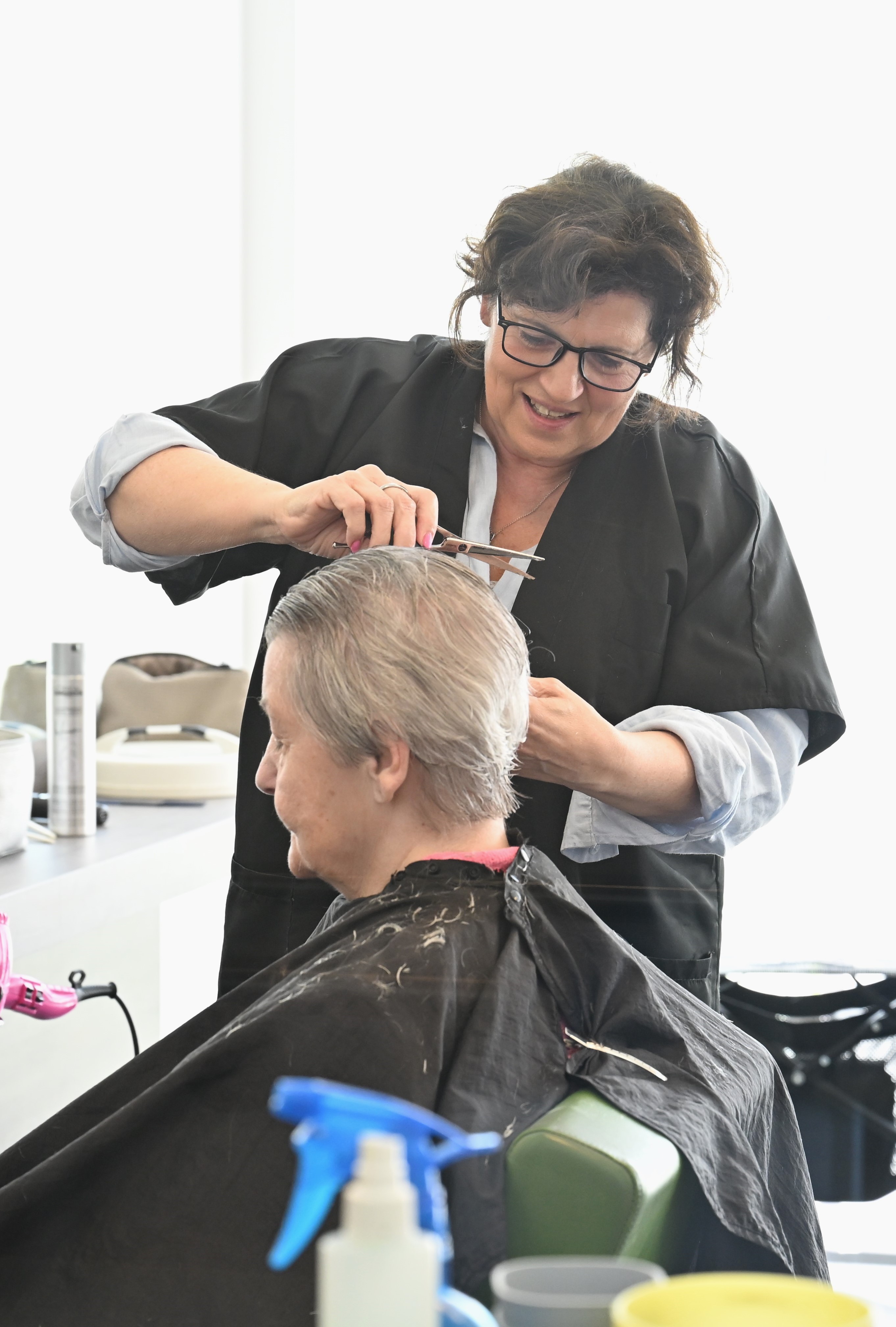 Haar wordt geknipt in kapsalon door kapster.