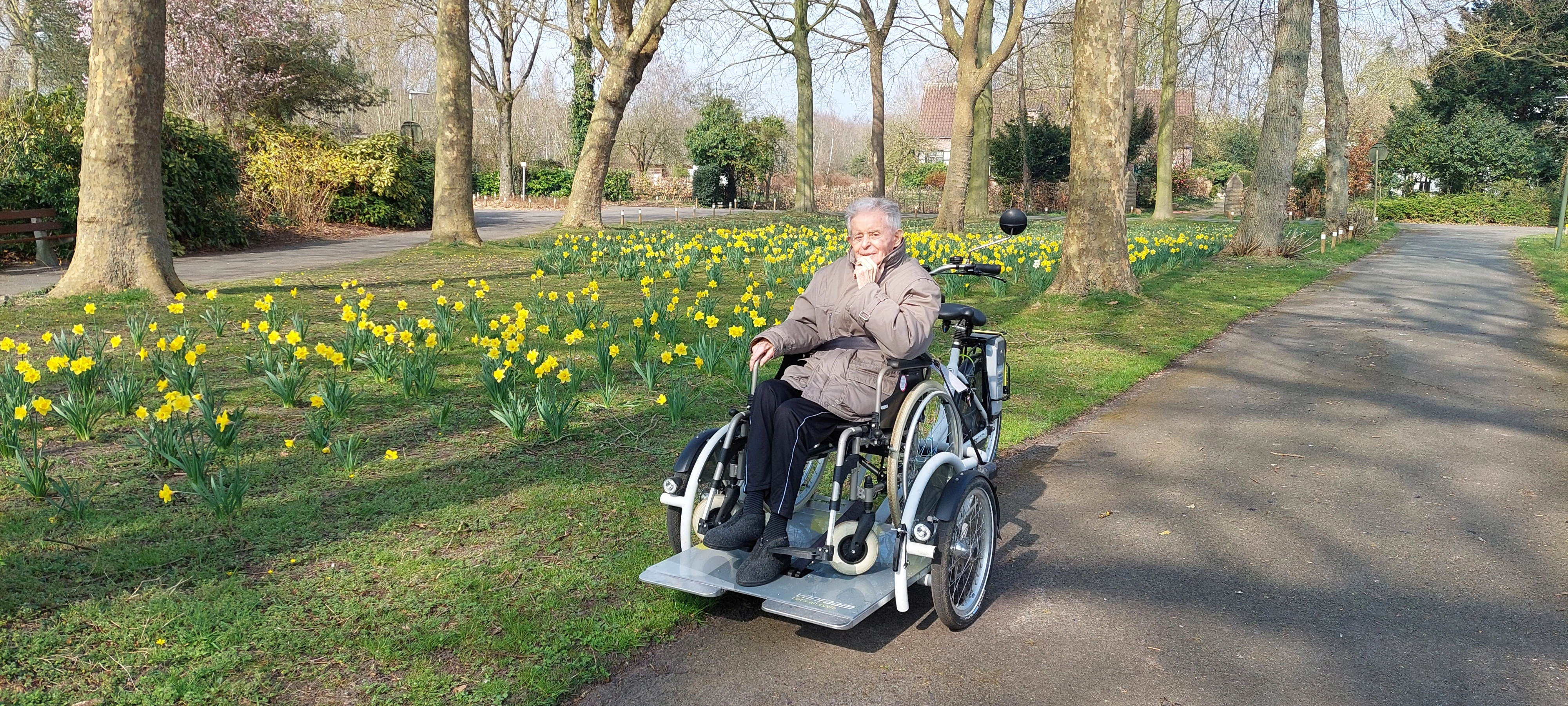 Bewoonster in rolstoel rijdt langs gras en bloemen