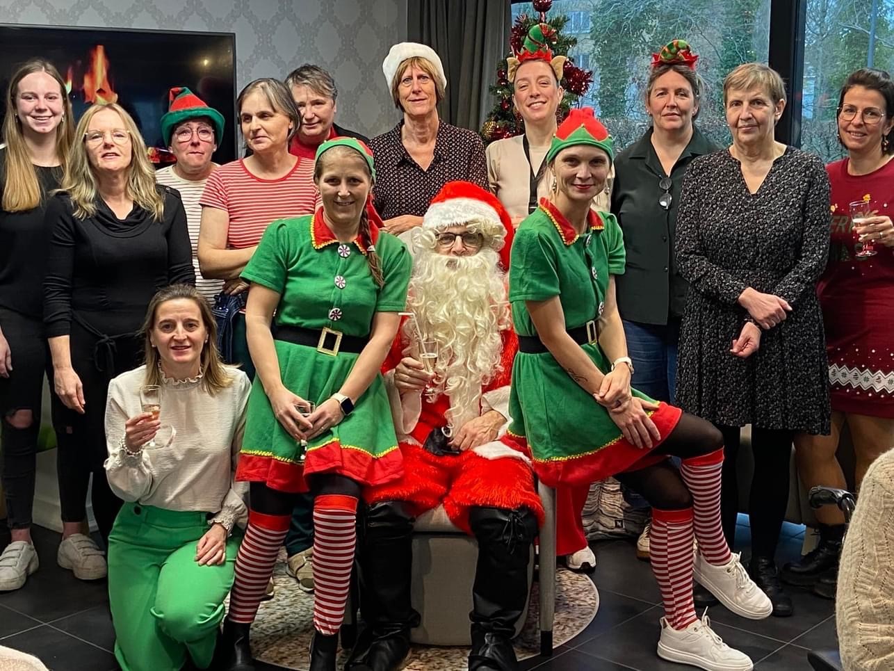 Medewerkers van Van Zuylen staan met leuke kerstkledij op de foto. In het midden zit de kerstman met aan zijn zijde twee kerstelfen.