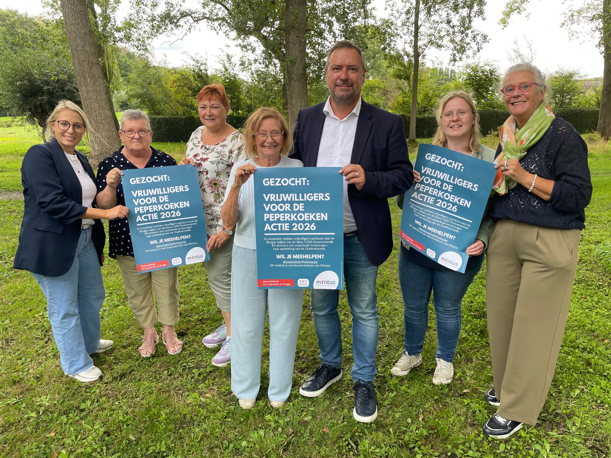 Mintus-voorzitter Pablo Annys poseert, samen met enkele vrijwilligers, met de affiche van de peperkoekenactie. 
