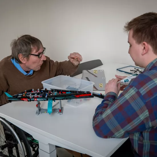 2 personen zijn een grijs modelvliegtuig aan het bouwen bouwen in Ons Huis Brugge