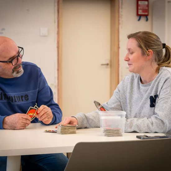 2 personen spelen Uno spelen aan tafel in Ons Huis Brugge.
